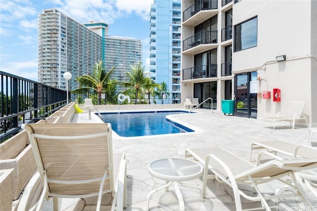 community pool with a view of city, a patio, and fence