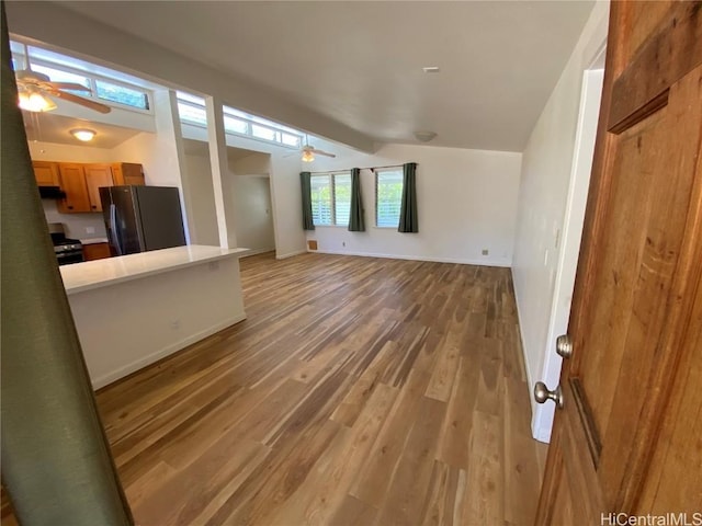 unfurnished living room with light wood finished floors, ceiling fan, and baseboards