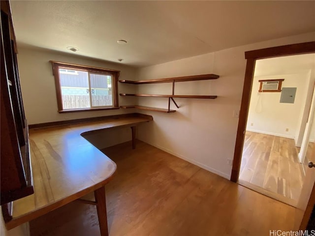 spacious closet with a wall unit AC, wood finished floors, and electric panel