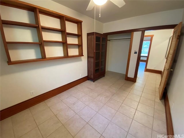 unfurnished bedroom featuring a ceiling fan, a closet, baseboards, and light tile patterned floors