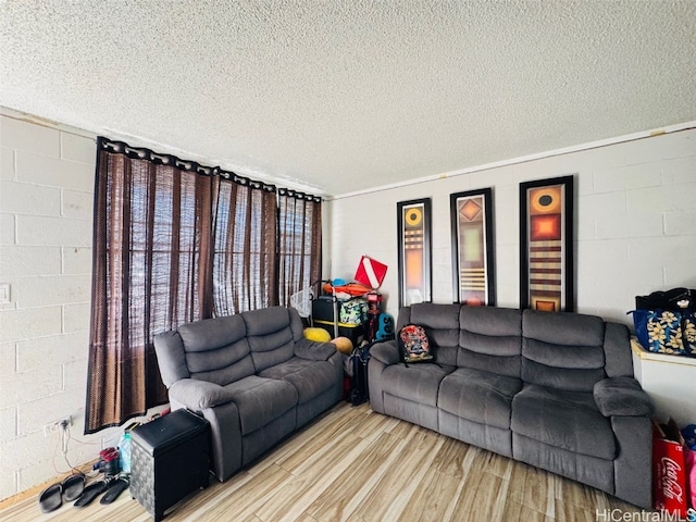 living room featuring concrete block wall, a textured ceiling, and wood finished floors