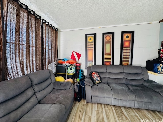 living area with wood finish floors, concrete block wall, and a textured ceiling