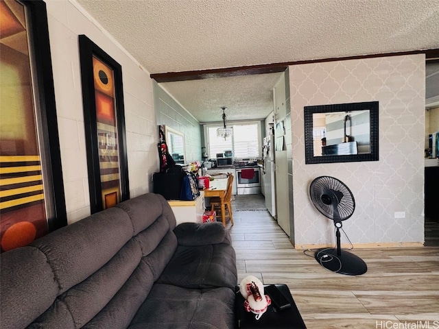 living area with concrete block wall, wallpapered walls, a textured ceiling, and wood finished floors