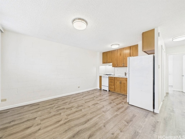 kitchen featuring light countertops, light wood-type flooring, brown cabinets, white appliances, and a textured ceiling