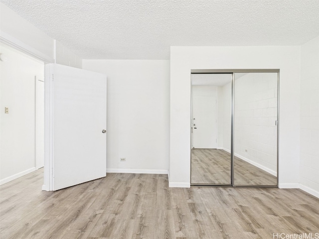 unfurnished bedroom with baseboards, wood finished floors, a closet, and a textured ceiling