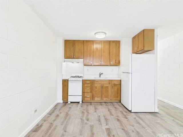 kitchen with white appliances, light wood finished floors, brown cabinets, and under cabinet range hood