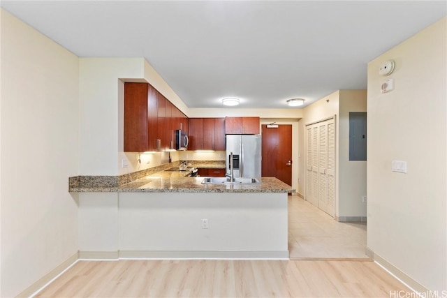 kitchen with stainless steel appliances, a peninsula, electric panel, and baseboards