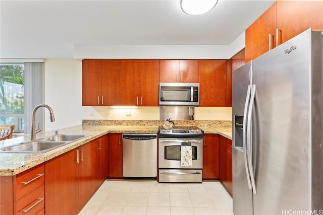 kitchen featuring light tile patterned floors, light stone counters, stainless steel appliances, a peninsula, and a sink