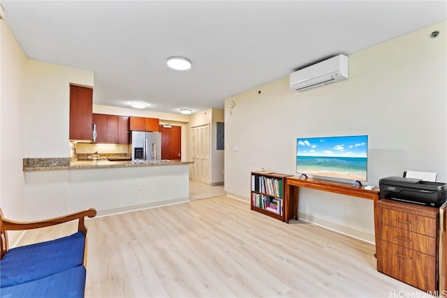 kitchen with light wood-type flooring, a wall mounted AC, stainless steel refrigerator with ice dispenser, and baseboards