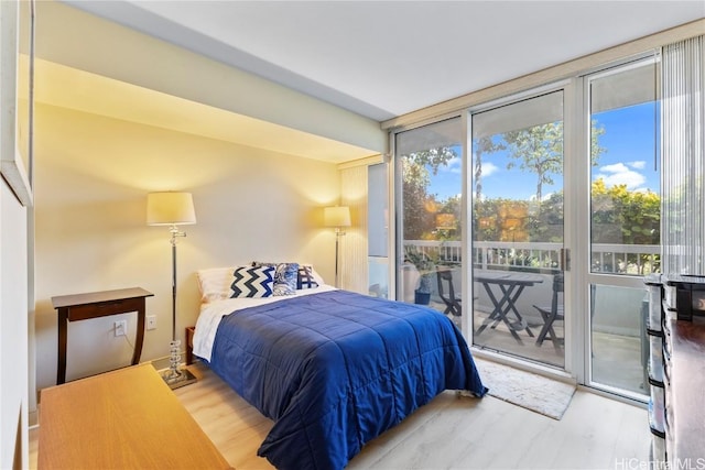 bedroom with a wall of windows, access to outside, and wood finished floors