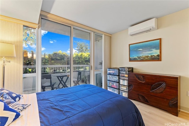 bedroom featuring an AC wall unit, access to outside, wood finished floors, and floor to ceiling windows