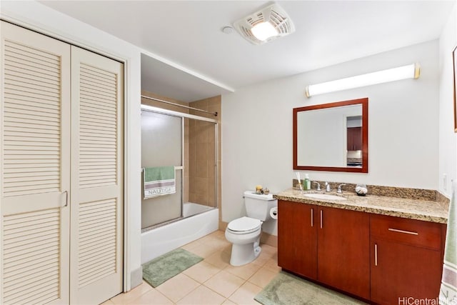 bathroom with tile patterned flooring, toilet, bath / shower combo with glass door, vanity, and a closet