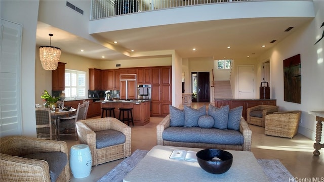 living area featuring a towering ceiling, visible vents, a notable chandelier, and recessed lighting