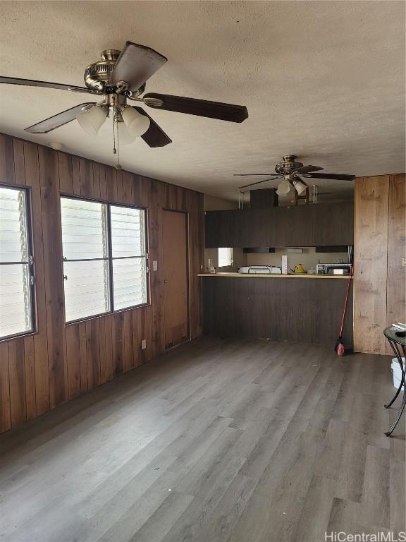 kitchen with a textured ceiling, wooden walls, and wood finished floors