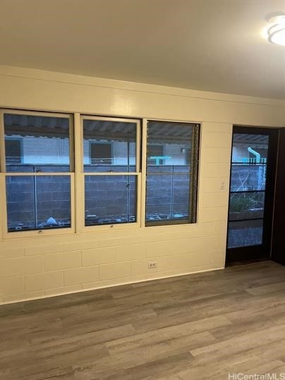 spare room with concrete block wall and wood finished floors