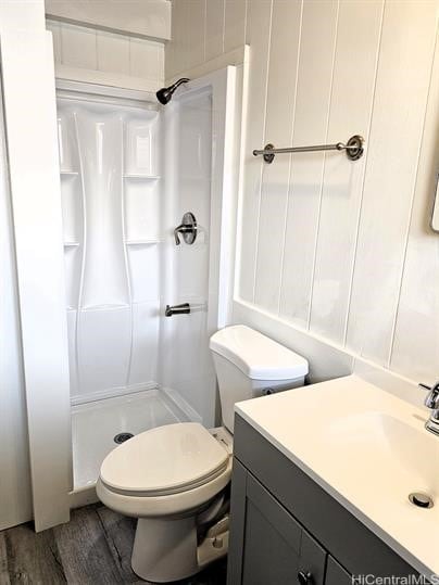 full bath with vanity, wood finished floors, a shower stall, and toilet