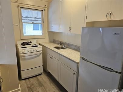 kitchen with light countertops, light wood-style flooring, white cabinets, a sink, and white appliances