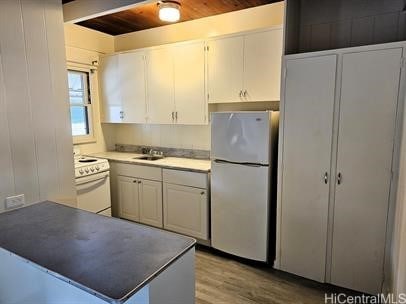 kitchen with light wood finished floors, wooden ceiling, white cabinetry, white appliances, and a peninsula