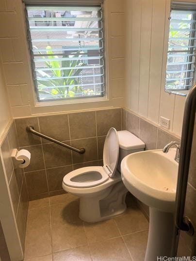 bathroom with tile walls, toilet, and tile patterned floors