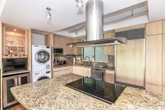 kitchen with wine cooler, island range hood, stacked washer / dryer, stovetop, and stainless steel microwave