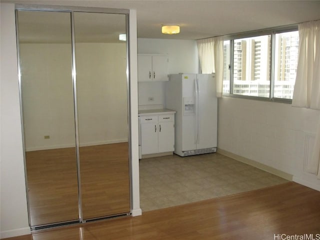 kitchen featuring light floors, white refrigerator with ice dispenser, white cabinetry, and light countertops