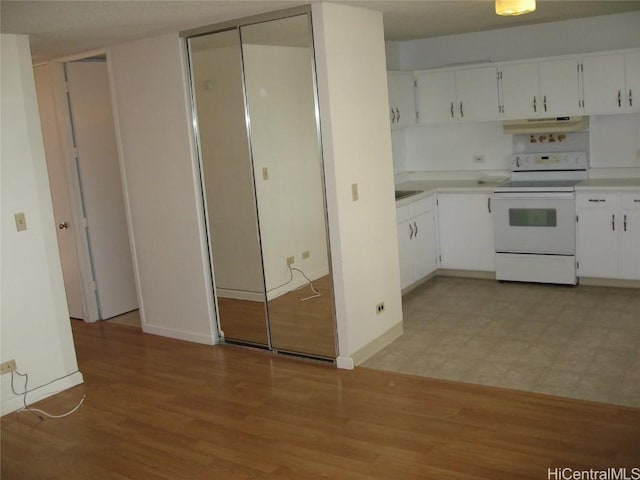 kitchen with light countertops, electric range, light wood-style flooring, and under cabinet range hood