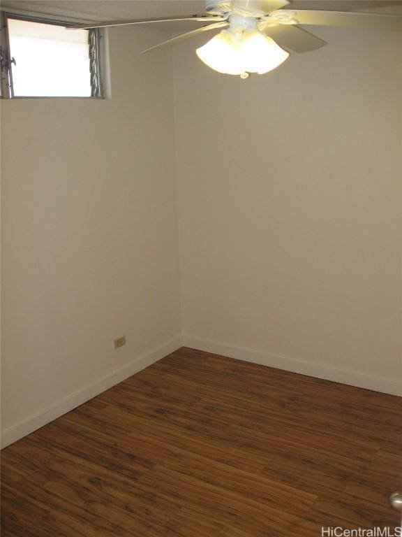 empty room with baseboards, a ceiling fan, and dark wood-type flooring