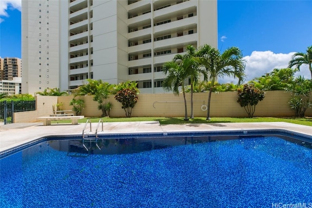 community pool with a patio area and fence