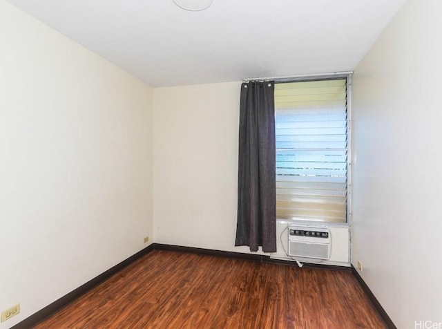 spare room with dark wood finished floors, baseboards, and a wall mounted air conditioner