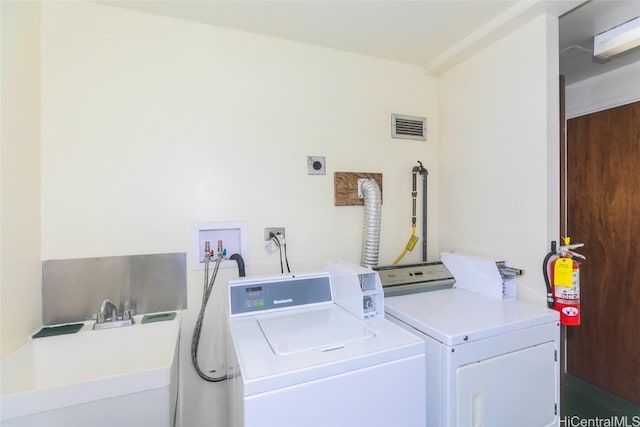 laundry area with visible vents, independent washer and dryer, and a sink