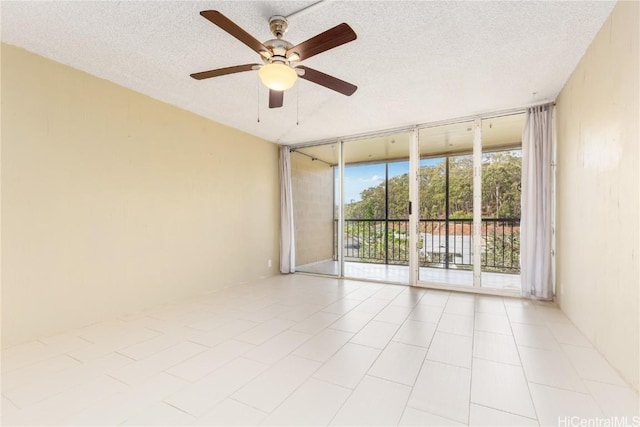 unfurnished room with a ceiling fan, expansive windows, and a textured ceiling