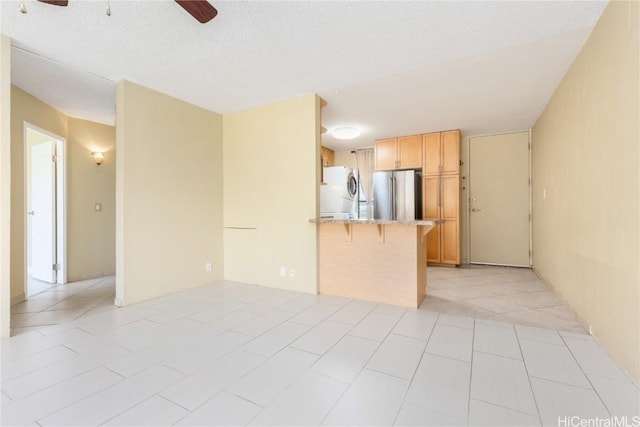 interior space featuring a ceiling fan, a textured ceiling, and light tile patterned floors