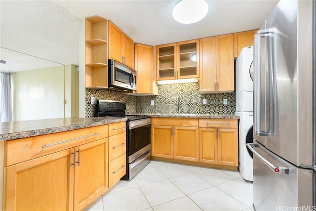 kitchen featuring glass insert cabinets, appliances with stainless steel finishes, a sink, open shelves, and backsplash