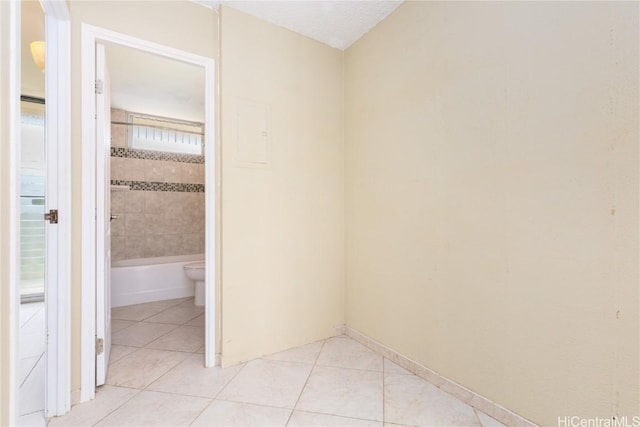 empty room featuring light tile patterned flooring, a textured ceiling, and baseboards