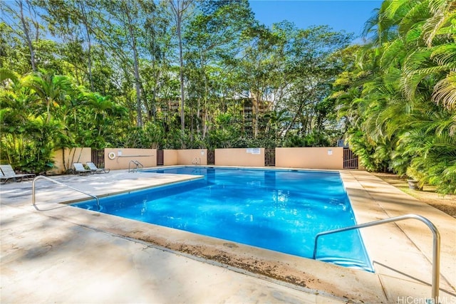 pool with a patio area and fence