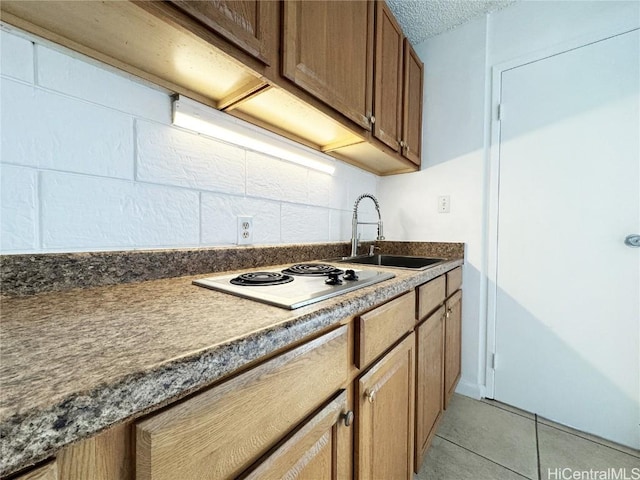 kitchen featuring dark countertops, light tile patterned floors, white electric stovetop, and a sink