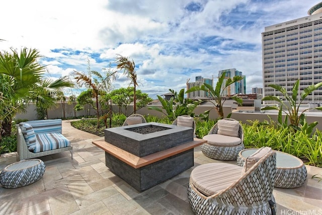 view of patio with a city view, a fire pit, and fence