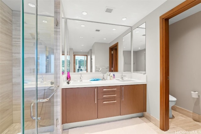 bathroom featuring visible vents, toilet, a sink, a shower stall, and double vanity