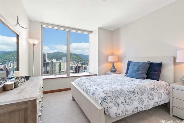 bedroom featuring a mountain view, light carpet, and baseboards