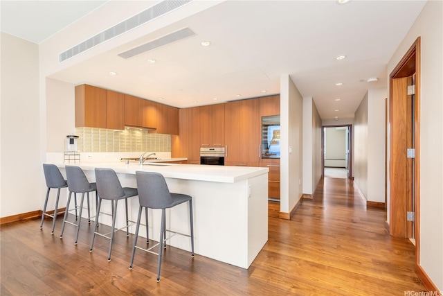 1555 Kapiolani Blvd Unit 1900, Honolulu, HI 96814 - kitchen with stainless steel oven, modern cabinets, a peninsula, light countertops, and brown cabinetry