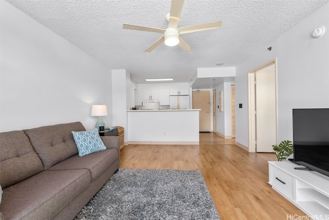 living area with light wood-style flooring, a textured ceiling, and ceiling fan