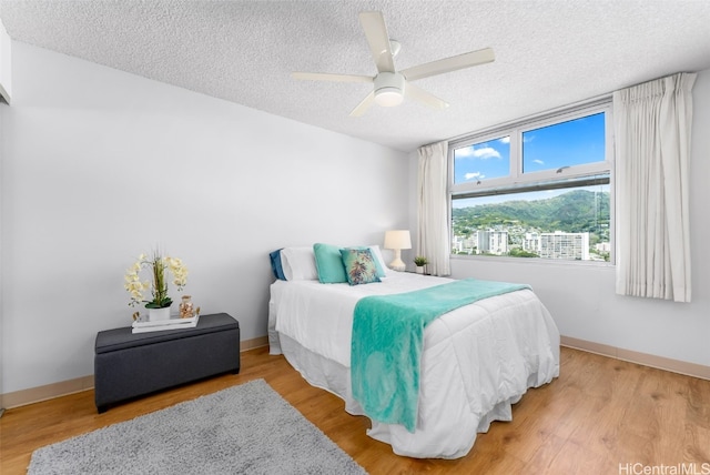 bedroom featuring a textured ceiling, a ceiling fan, baseboards, and wood finished floors