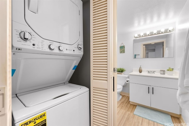 clothes washing area with stacked washer and dryer, laundry area, and light wood finished floors