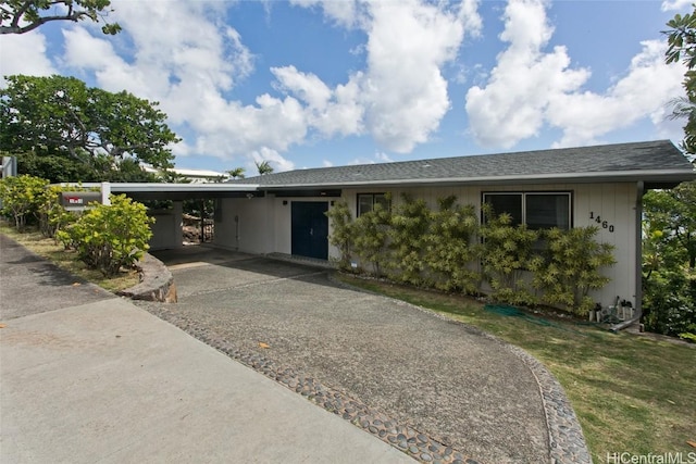 ranch-style house featuring an attached carport, driveway, and a shingled roof