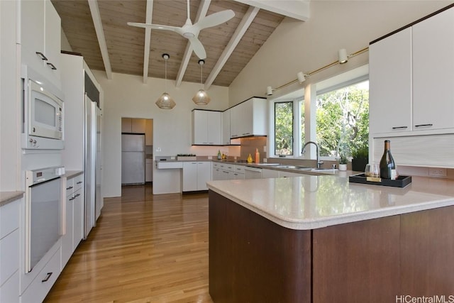 kitchen featuring beam ceiling, a sink, white appliances, a peninsula, and wooden ceiling