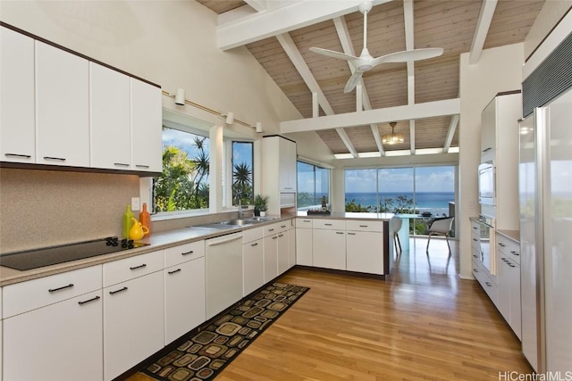 kitchen with wall oven, black electric stovetop, dishwasher, beam ceiling, and a peninsula