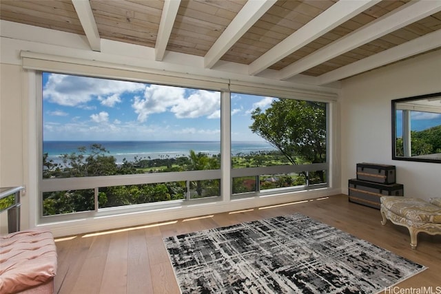 living area with beam ceiling, wood finished floors, wood ceiling, and a water view