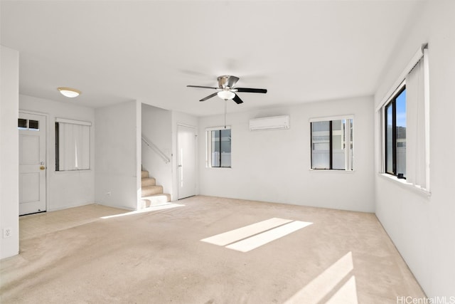 spare room with an AC wall unit, stairway, and a ceiling fan