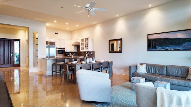 living room with light tile patterned floors, baseboards, a ceiling fan, a towering ceiling, and recessed lighting