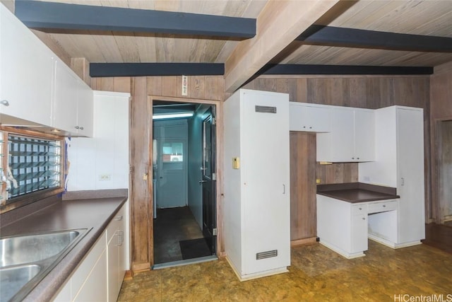 kitchen with beam ceiling, wood walls, visible vents, and white cabinets